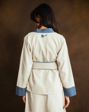 Close-up of the back of the cream wool-blend kimono jacket showing fabric texture and blue trim.