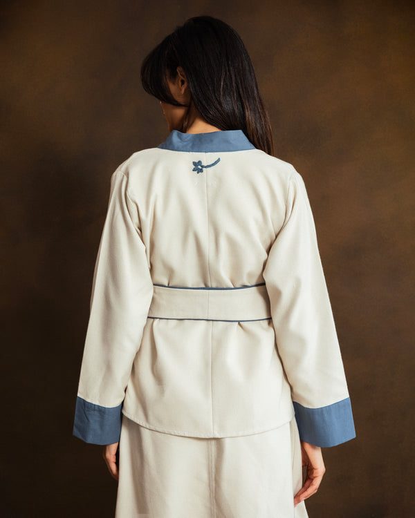 Close-up of the back of the cream wool-blend kimono jacket showing fabric texture and blue trim.