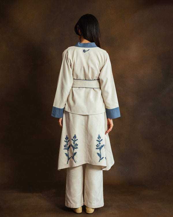 Back view of cream wool-blend kimono jacket with blue gabardine trim and matching trousers.