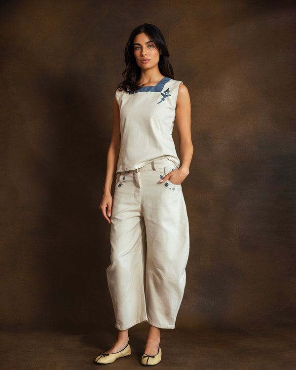 Model wearing cream wool-blend Mosaico Bubble Pants with hand-embroidered mosaic detailing and raffia trim along the pockets.