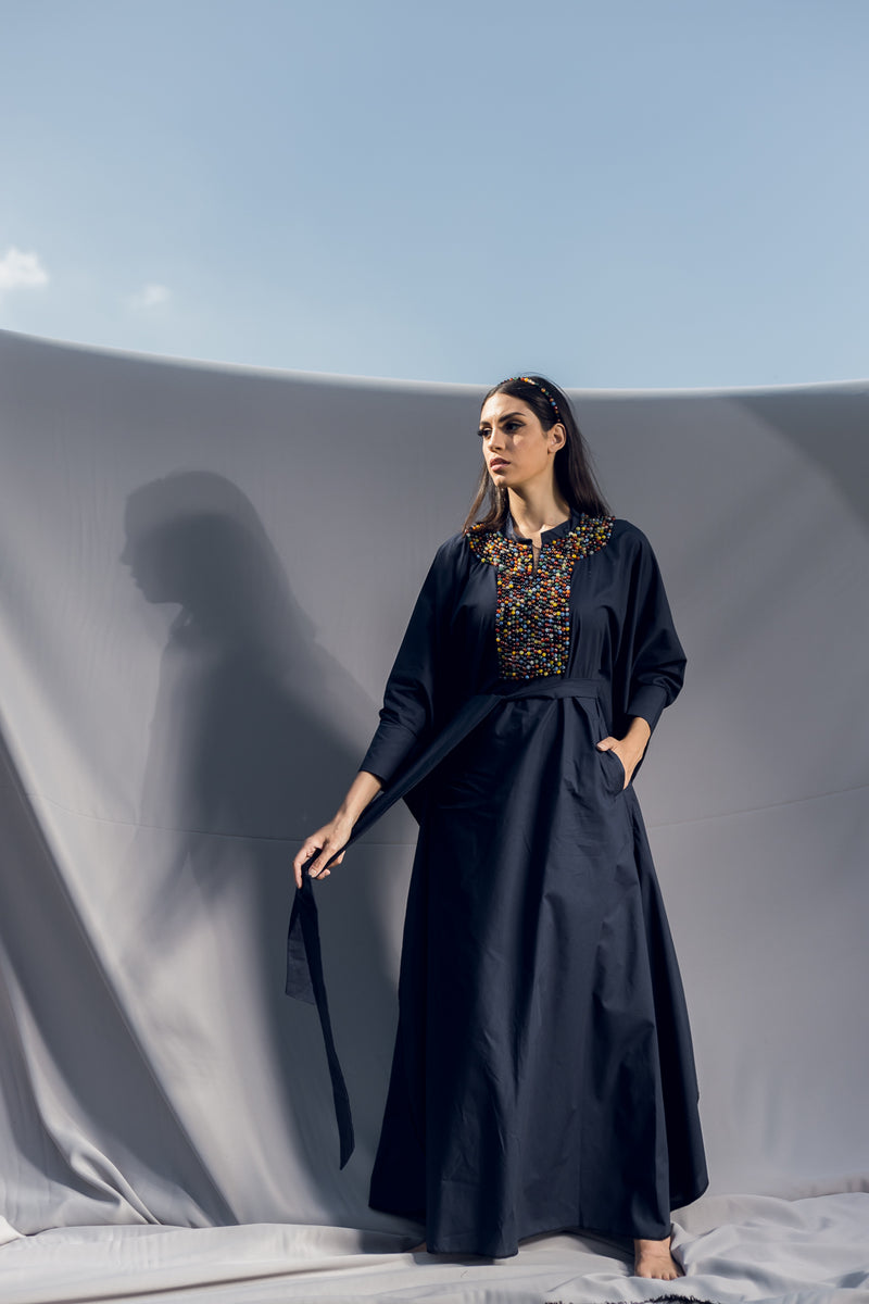 A long sleeve kaftan made of navy blue poplin cotton detailed by a lose fit, light collar, soft belt and easy-going pockets. Embellished by hand embroidered Multicolor Precious Stone beads creating a vibrant energy. Best paired with the Multicolor Precious Stone Headband for a full look.
